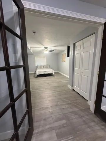 Spacious primary hallway with wood-finish flooring, ceiling fan, and access to multiple rooms