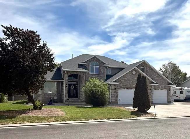 Two-story residence featuring a brick and stone facade, arched entryway, and multiple gables