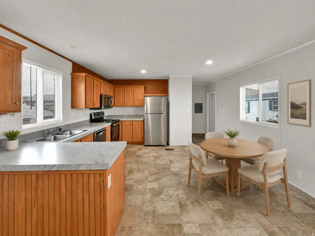 Kitchen with wood-finish cabinetry, stainless steel appliances, dual basin sink, and ample counter space