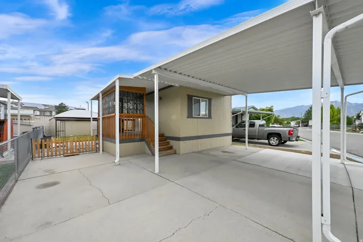 Covered carport, concrete driveway, wood deck with railing, exterior stairs, fenced yard area
