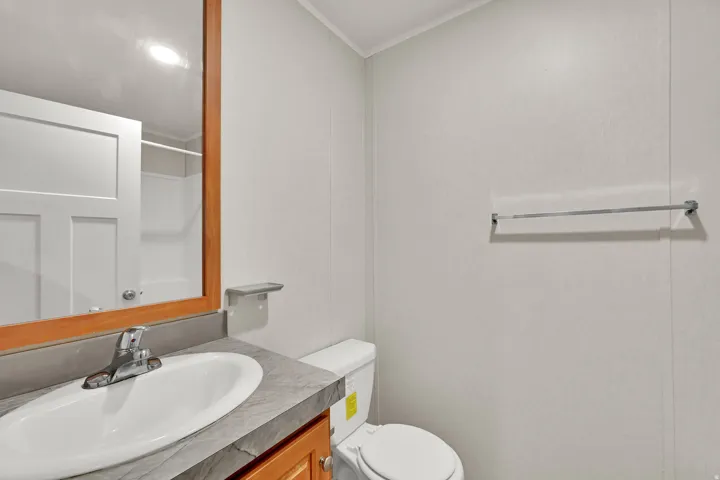 Modern master bathroom featuring a circular ceramic sink set atop a wood-finish vanity with gray countertop, chrome faucet, and integrated storage