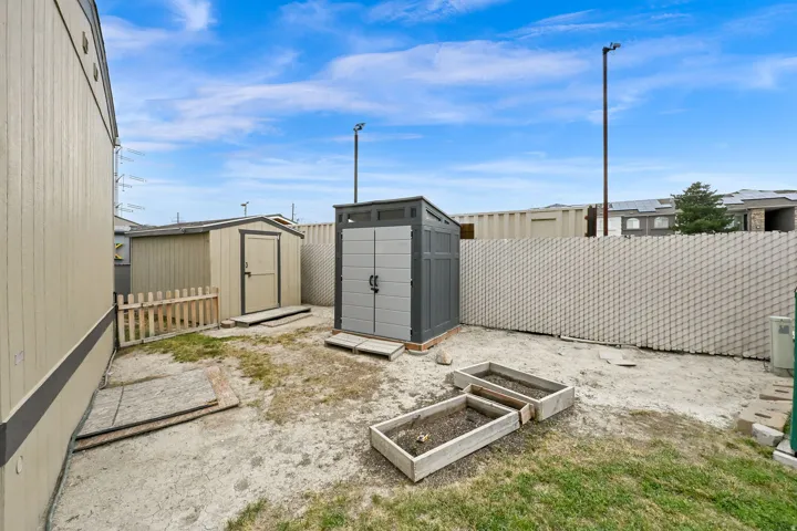 Two outdoor storage sheds, garden beds, and a perimeter fence