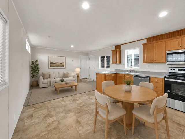 Open-concept living area with integrated kitchen and dining, featuring wood-finish cabinetry, stainless steel appliances, and recessed lighting