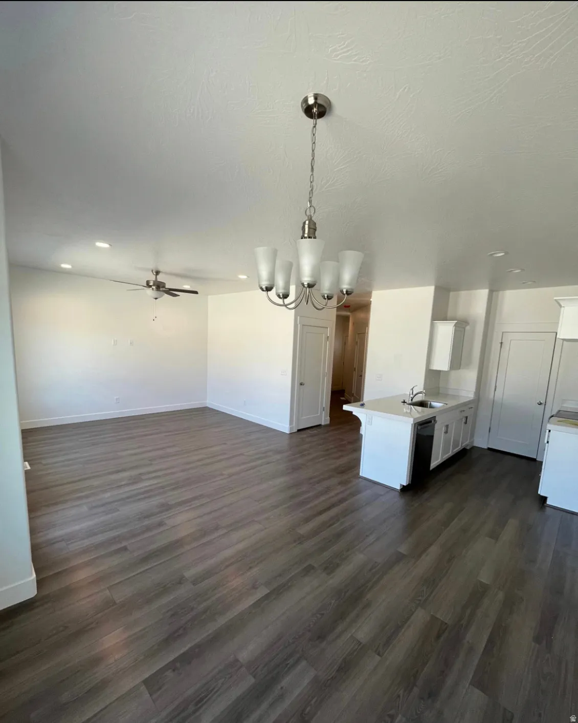 Wood-finish flooring throughout, brushed nickel chandelier, recessed lighting, ceiling fan, and a kitchen island with an undermount sink
