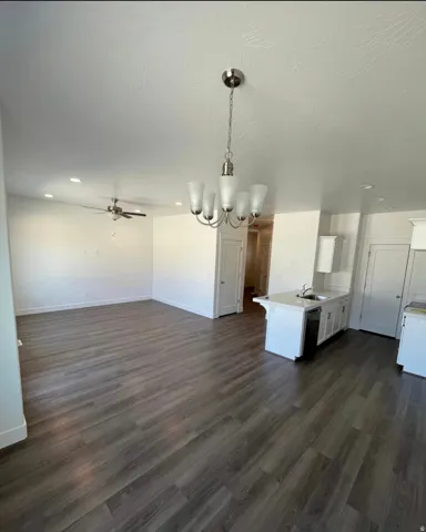 Wood-finish flooring throughout, brushed nickel chandelier, recessed lighting, ceiling fan, and a kitchen island with an undermount sink