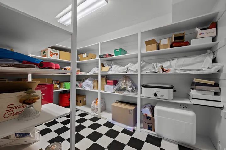 Extensive built-in shelving with a black and white checkerboard floor and overhead fluorescent lighting