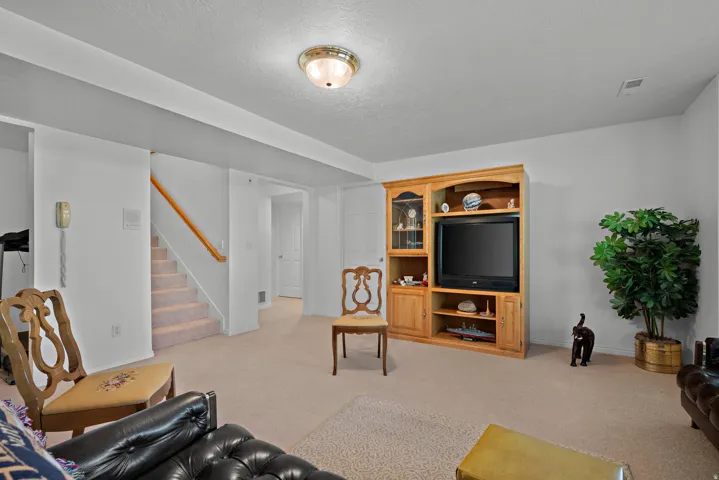 Neutral wall paint, recessed lighting, wood handrailing, built-in media cabinetry, and carpet flooring