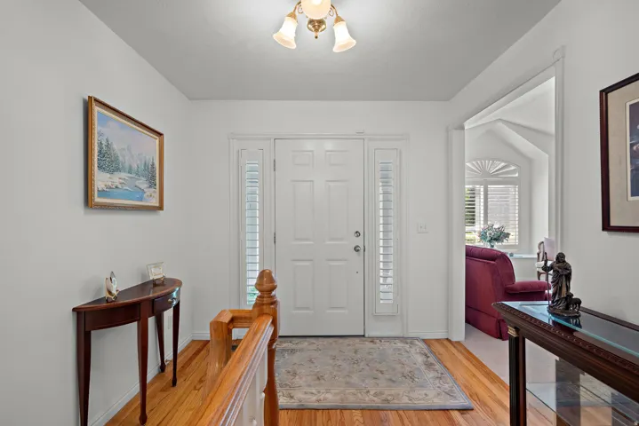 Entryway with hardwood flooring, a paneled door, and sidelight windows with shutters