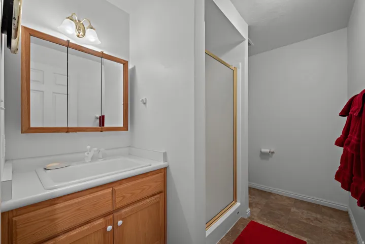 Bathroom with wood-finish vanity, integrated sink, and white countertop