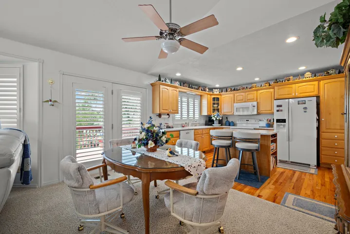 Kitchen featuring wood-finish cabinetry, white appliances, and a central island with bar seating
