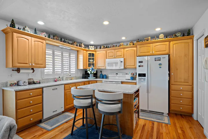 Spacious kitchen featuring wood-finish cabinetry, light-toned countertops, and wood-finish flooring