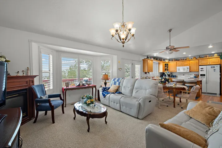 Bay windows with plantation shutters, wood-finish mantel, kitchen with wood cabinetry, stainless steel refrigerator, and recessed lighting