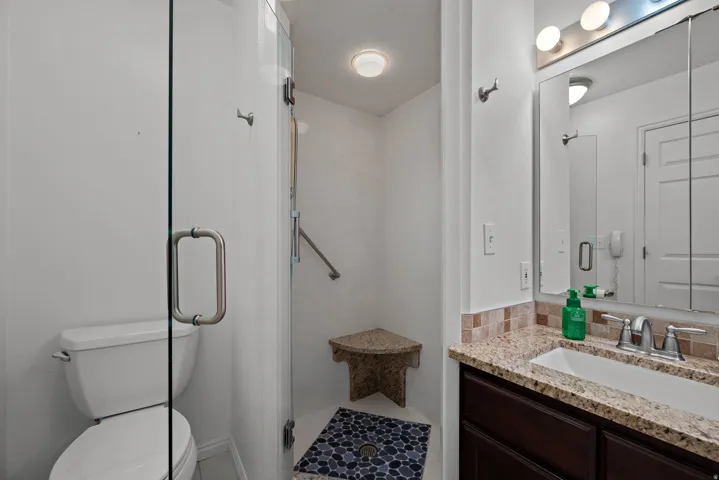 Glass-enclosed shower with a built-in corner bench and mosaic tile flooring