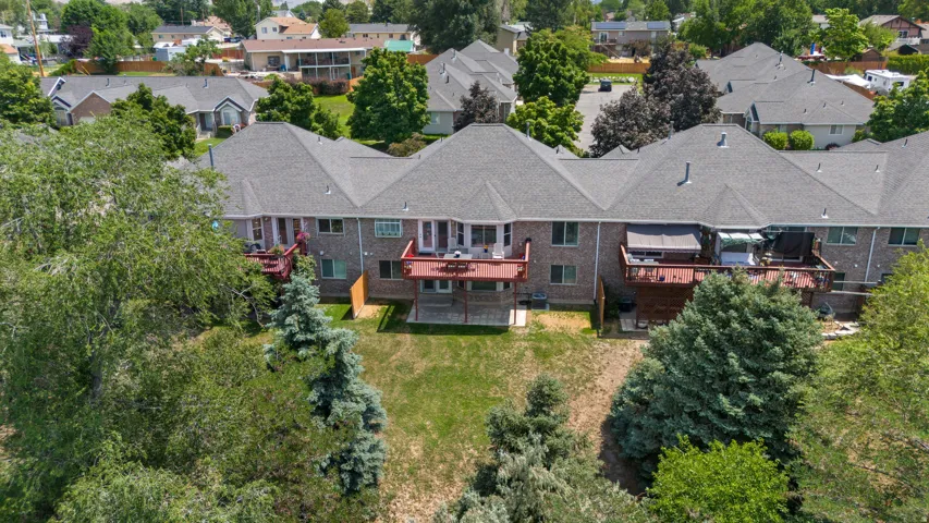 Brick exterior with gray shingle roofing, multiple wooden decks, and a sloped, grassy backyard