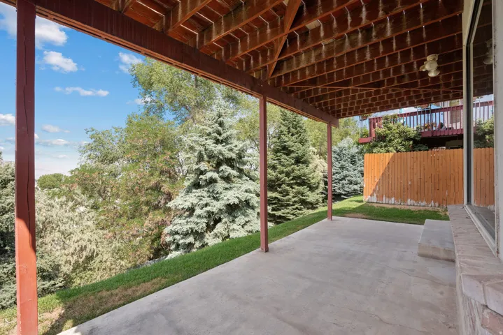 Covered patio with a concrete surface, supported by exposed wood beams and columns