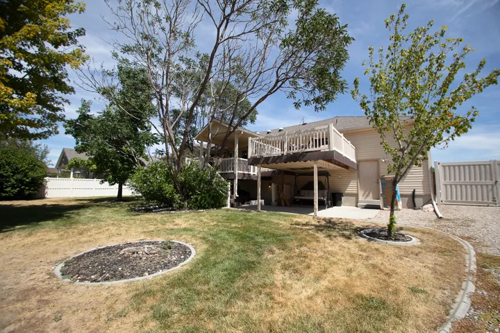 Multi-level rear deck with white railing, covered patio area, and mature trees