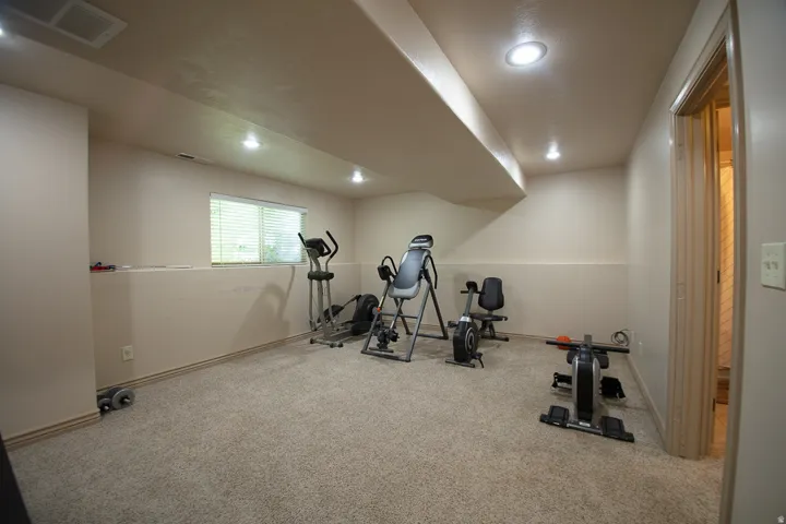 Recessed ceiling lighting, neutral carpeting, window with blinds, bi-fold door, and light-toned walls