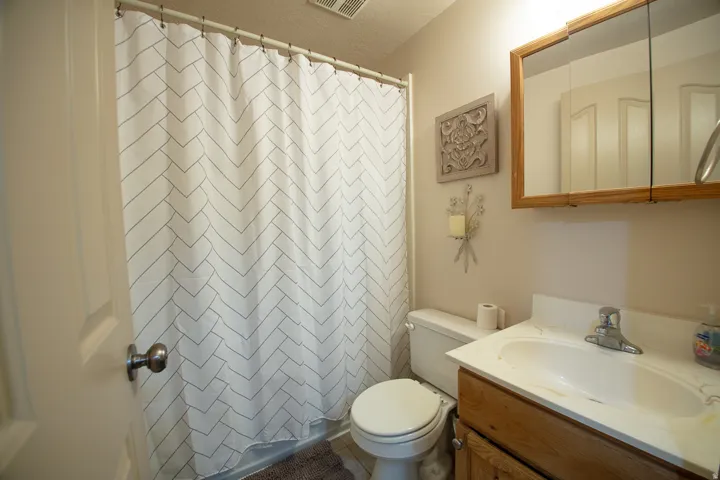 Bathroom featuring a vanity with an integrated sink, wood-finish cabinetry, a wall-mounted medicine cabinet with a mirror, and a toilet