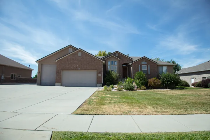 Brick exterior with a multi-car driveway, attached garage, and established front landscaping