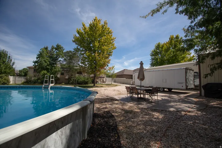Above-ground pool with ladder access, gravel landscaping, and mature foliage