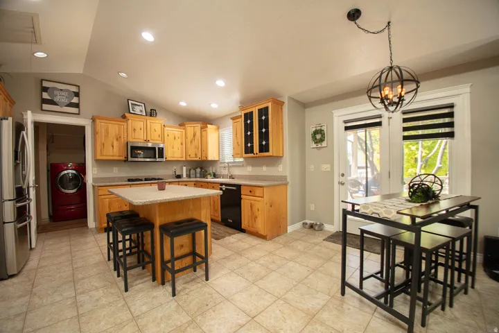Kitchen featuring wood cabinetry, stainless steel appliances, a kitchen island with seating, and tile flooring