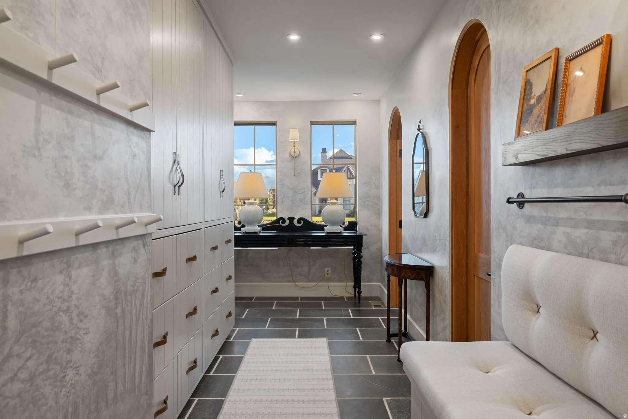 Built-in storage cabinetry, arched doorways, tiled flooring, recessed lighting, and wall-mounted sconces