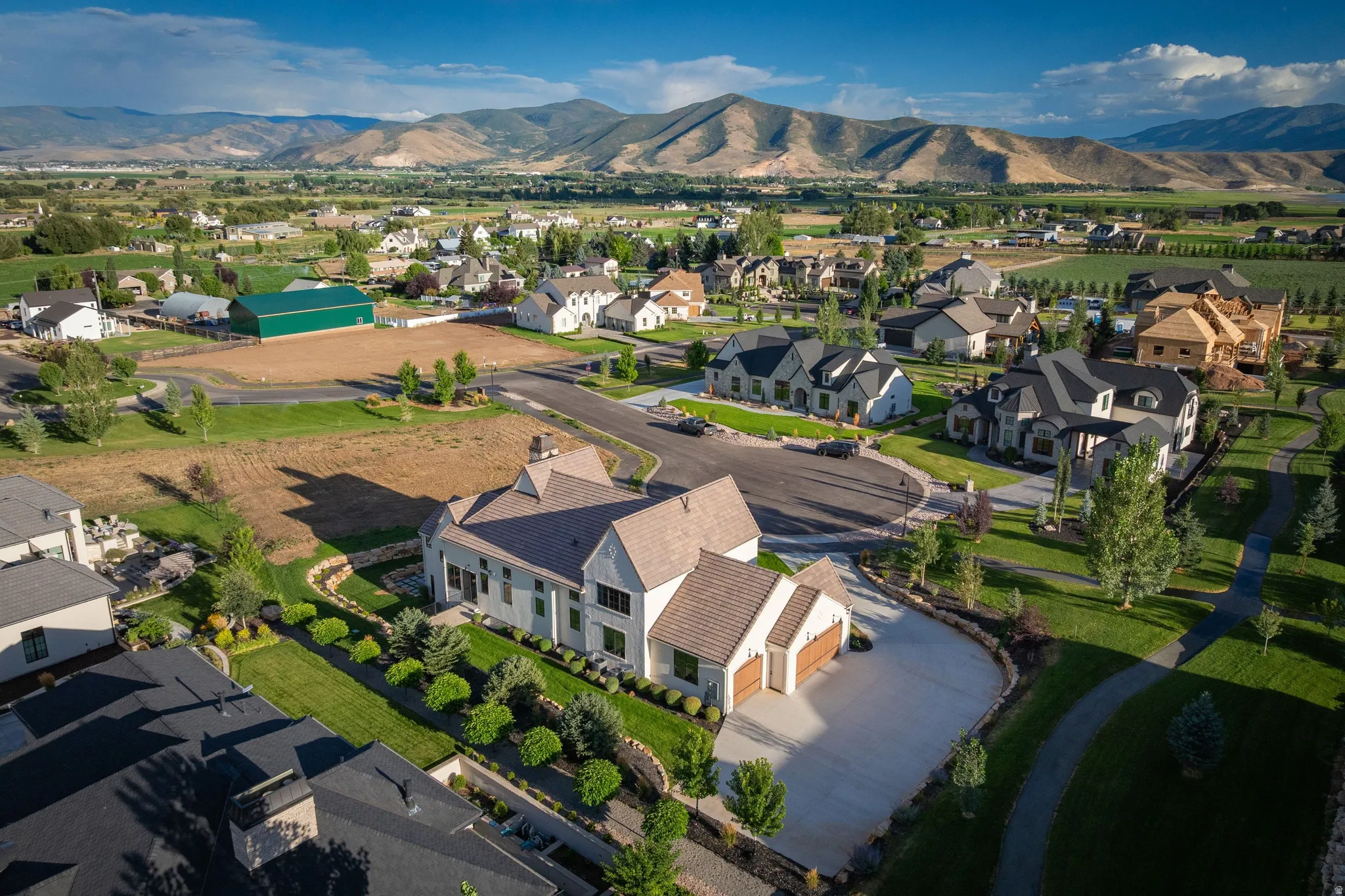 Elegant residence with a cream and brown exterior featuring a curved architectural entry, situated on an expansive manicured lot