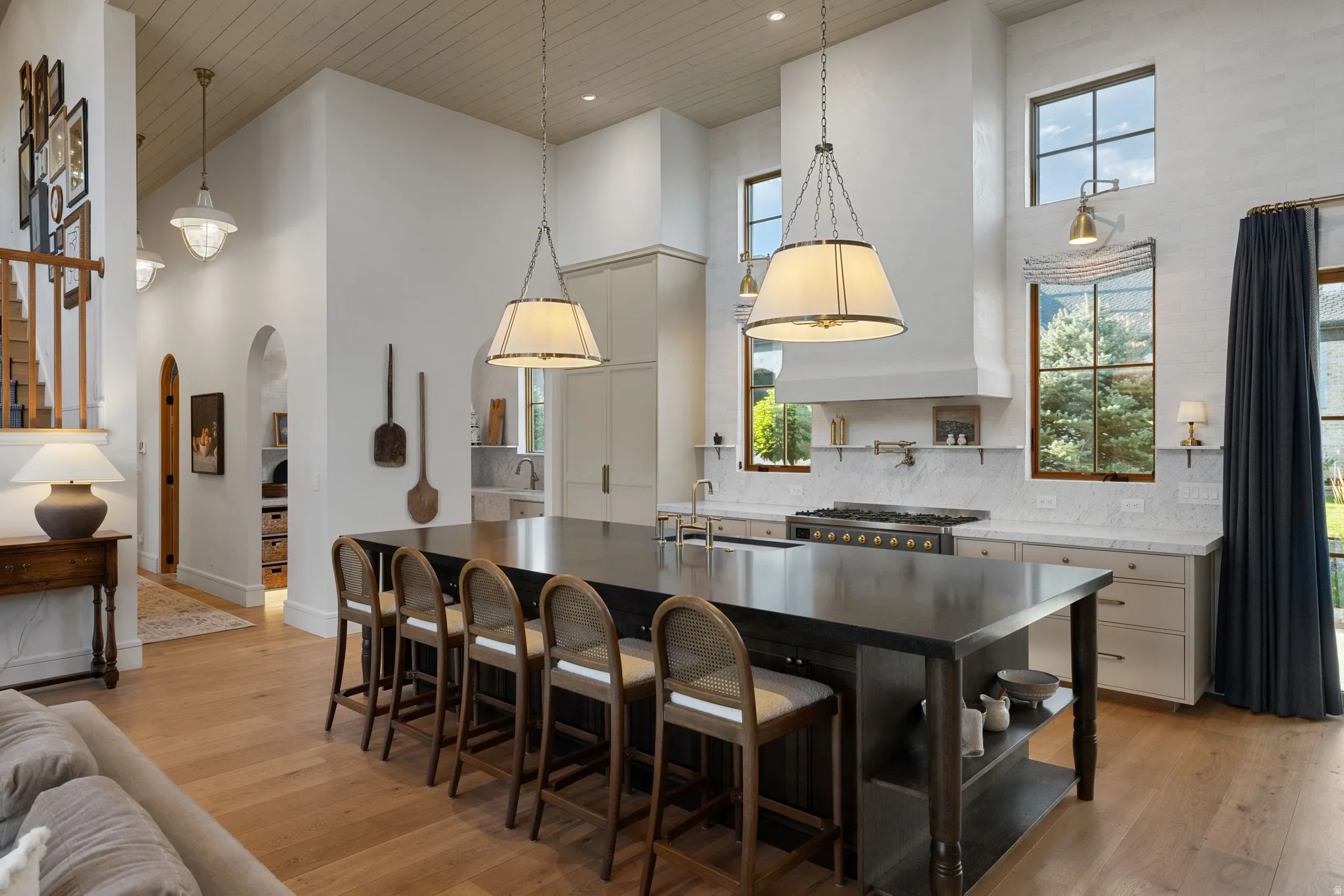 Chef's kitchen anchored by a substantial island with black-finished cabinetry and stainless steel countertop, paired with professional-grade gas range and integrated appliances