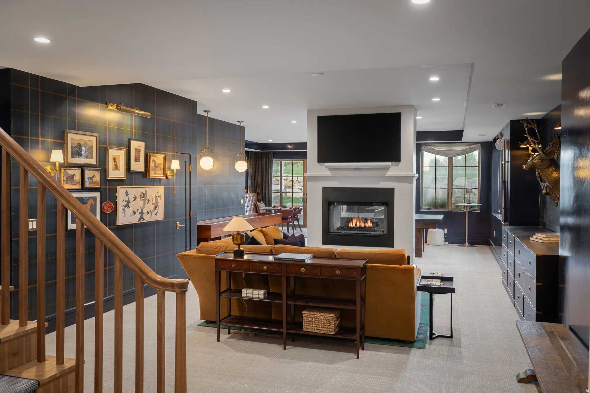 Open-concept living area featuring dark shiplap accent walls, recessed ceiling lighting, and a linear gas fireplace with a surround-mount television