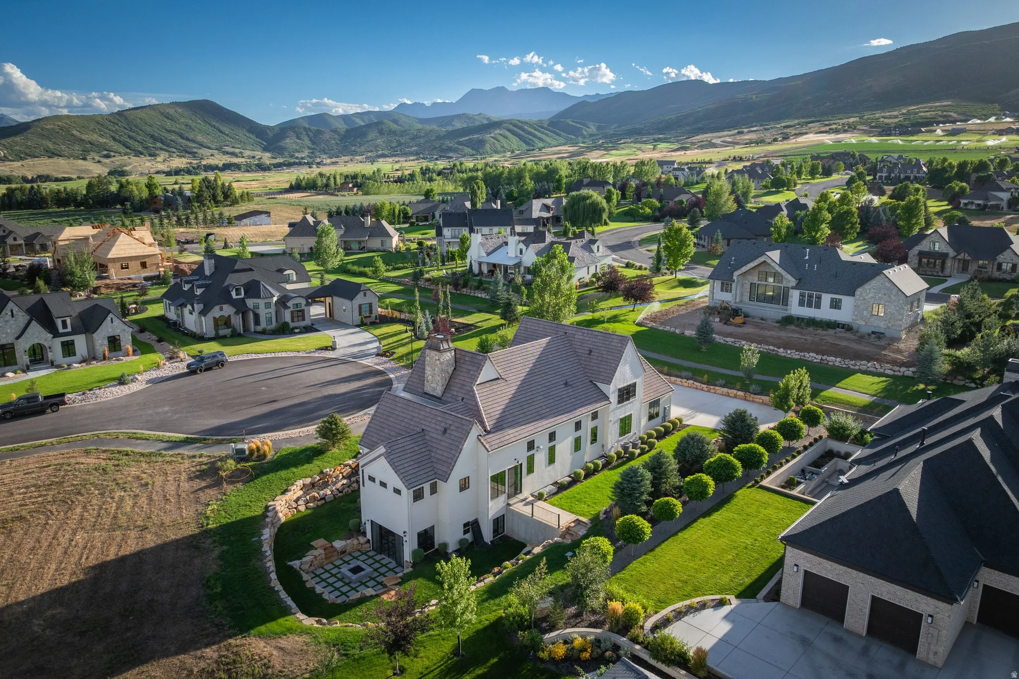 Elegant residence set on expansive grounds featuring manicured lawns, mature landscaping, and mountain vistas