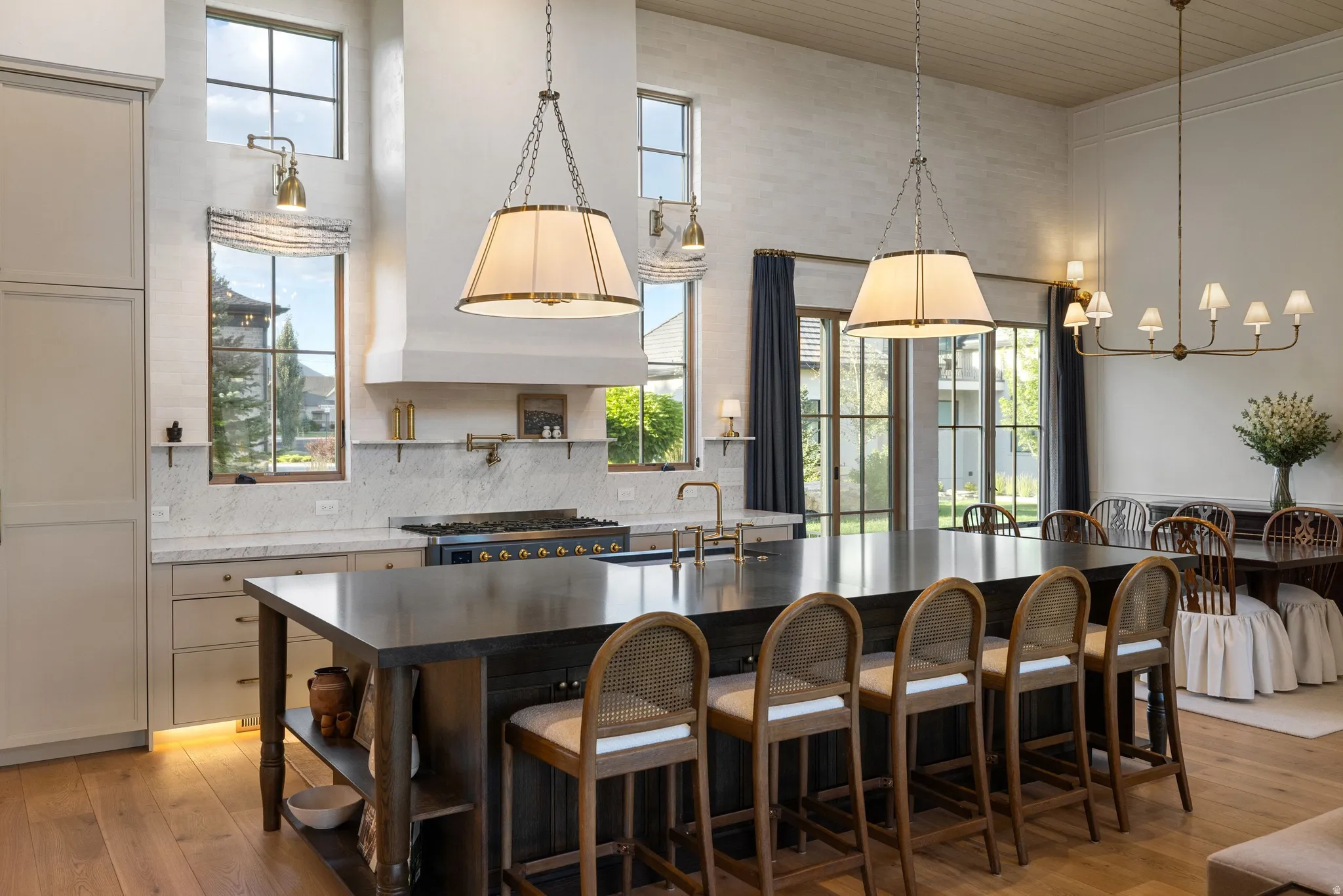Chef's kitchen featuring a six-burner gas range, stainless steel appliances, and a substantial waterfall-edge island with seating for multiple guests