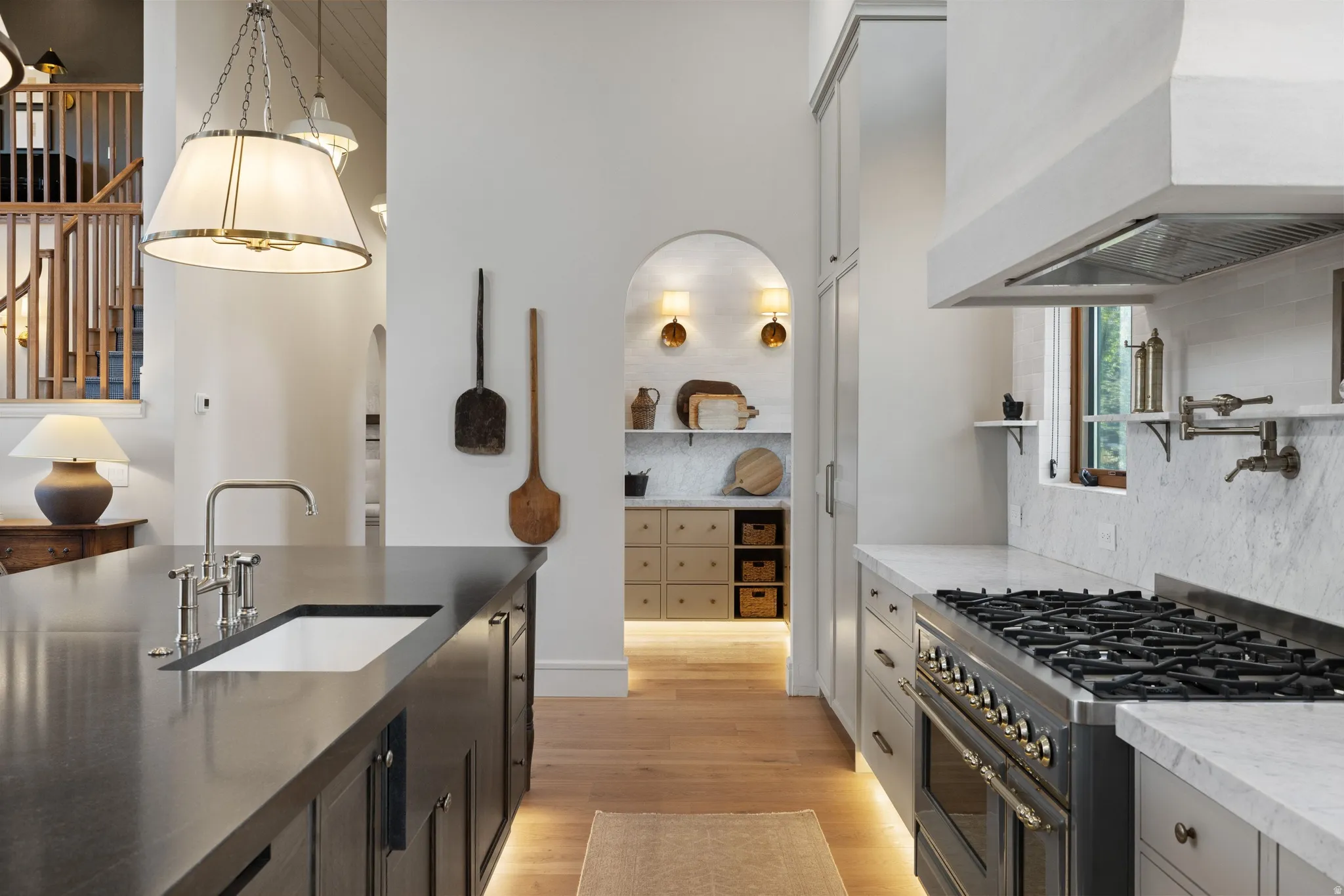 Chef's kitchen featuring professional-grade dual fuel range with six burners, stainless steel countertops, marble subway tile backsplash, custom cabinetry with integrated storage, and pendant lighting suspended from coffered ceiling details