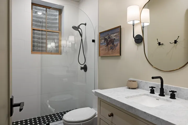 Walk-in shower with clear glass enclosure and black and white patterned tile flooring