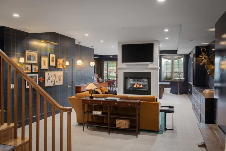 Open-concept living area featuring dark shiplap accent walls, recessed ceiling lighting, and a linear gas fireplace with a surround-mount television