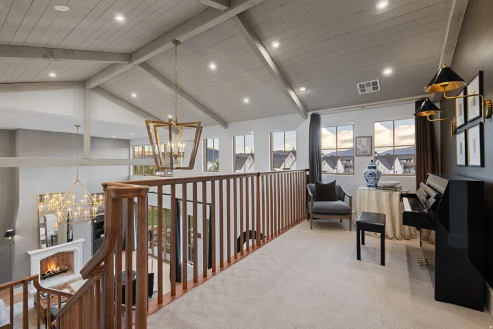 Vaulted shiplap ceiling with exposed beams, wood spindle railing, recessed lighting, and multiple windows
