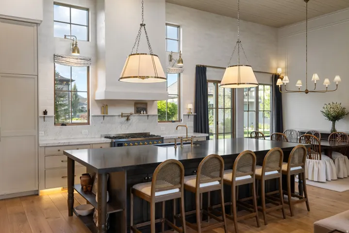 Chef's kitchen featuring a six-burner gas range, stainless steel appliances, and a substantial waterfall-edge island with seating for multiple guests