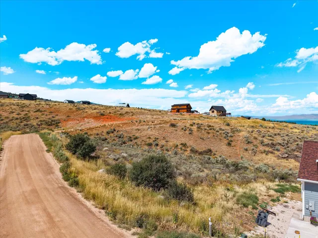 Expansive rural property featuring a long private driveway with natural terrain, native vegetation and sagebrush landscaping, and panoramic vistas of water and distant mountains under open sky