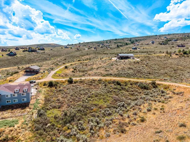 Sprawling high-desert property featuring a modern residence with board-and-batten siding, situated on expansive acreage with native vegetation and mature sagebrush landscaping