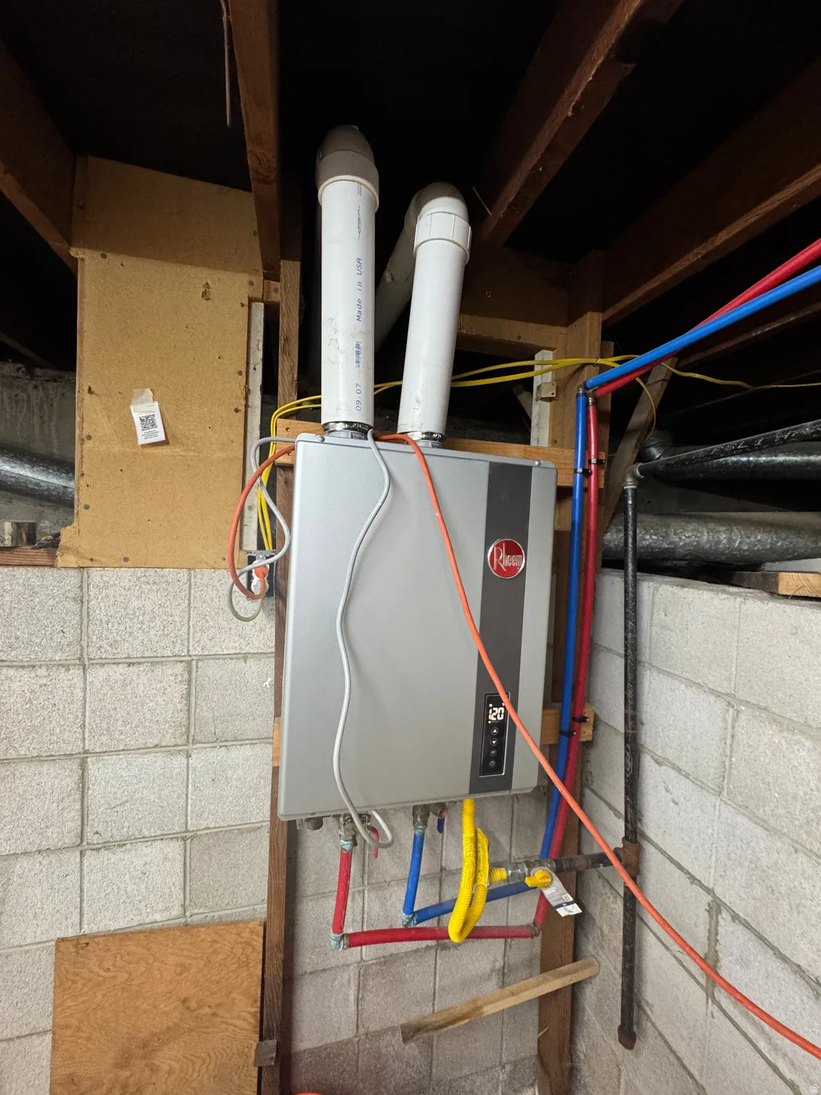Tankless water heater with visible plumbing and venting