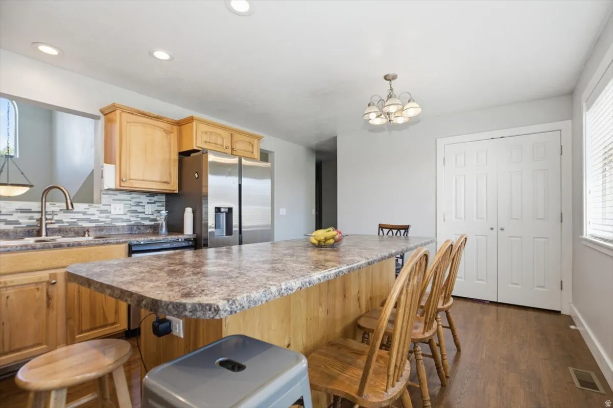 Kitchen featuring wood-finish cabinetry, stainless steel refrigerator, and a large island with countertop seating
