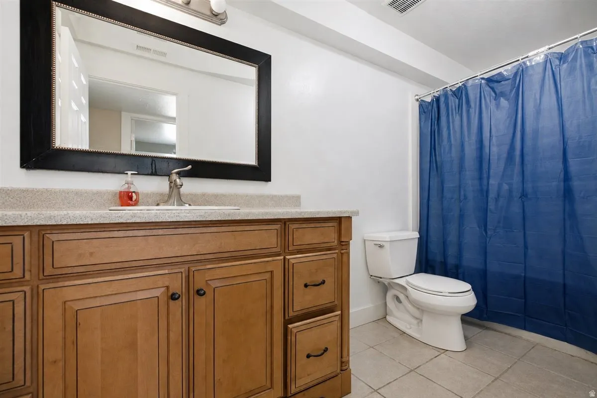 Vanity with wood-finish cabinetry, light-toned countertop, and integrated sink