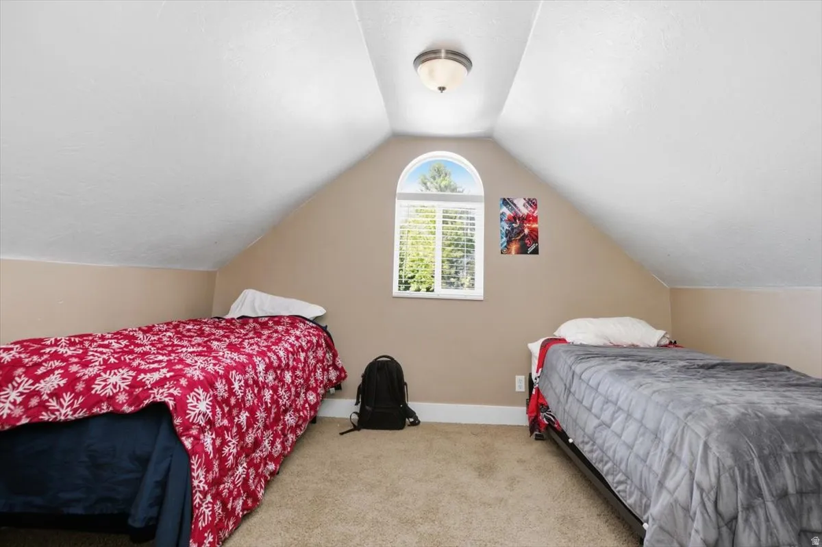 Vaulted ceiling with an arched window, featuring carpeted flooring and a semi-flush mount light fixture