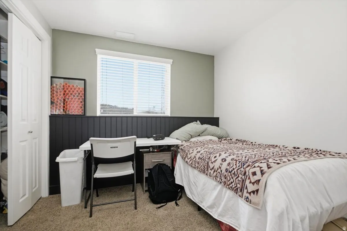 Double-pane window with white blinds, dark wood-finish wainscoting, and a neutral carpeted floor