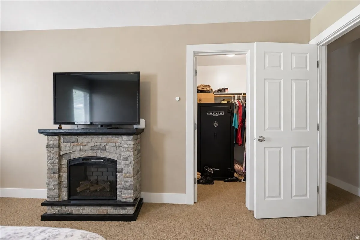 Stone-clad fireplace with mantel, recessed firebox, and carpeted flooring