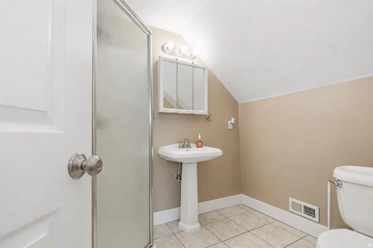 Bright bathroom featuring a pedestal sink with chrome fixtures, ceramic tile flooring, and neutral two-tone walls
