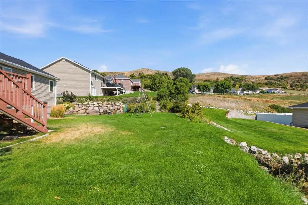 Expansive green lawn with a rock retaining wall and surrounding hillside