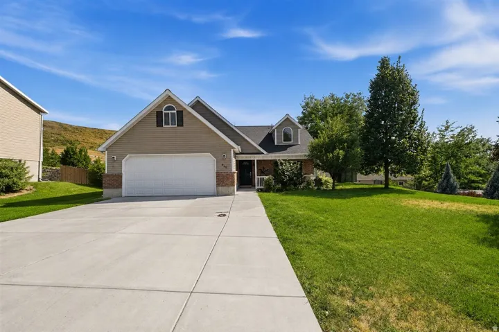 Siding exterior with brick accents, attached two-car garage, concrete driveway, and front lawn