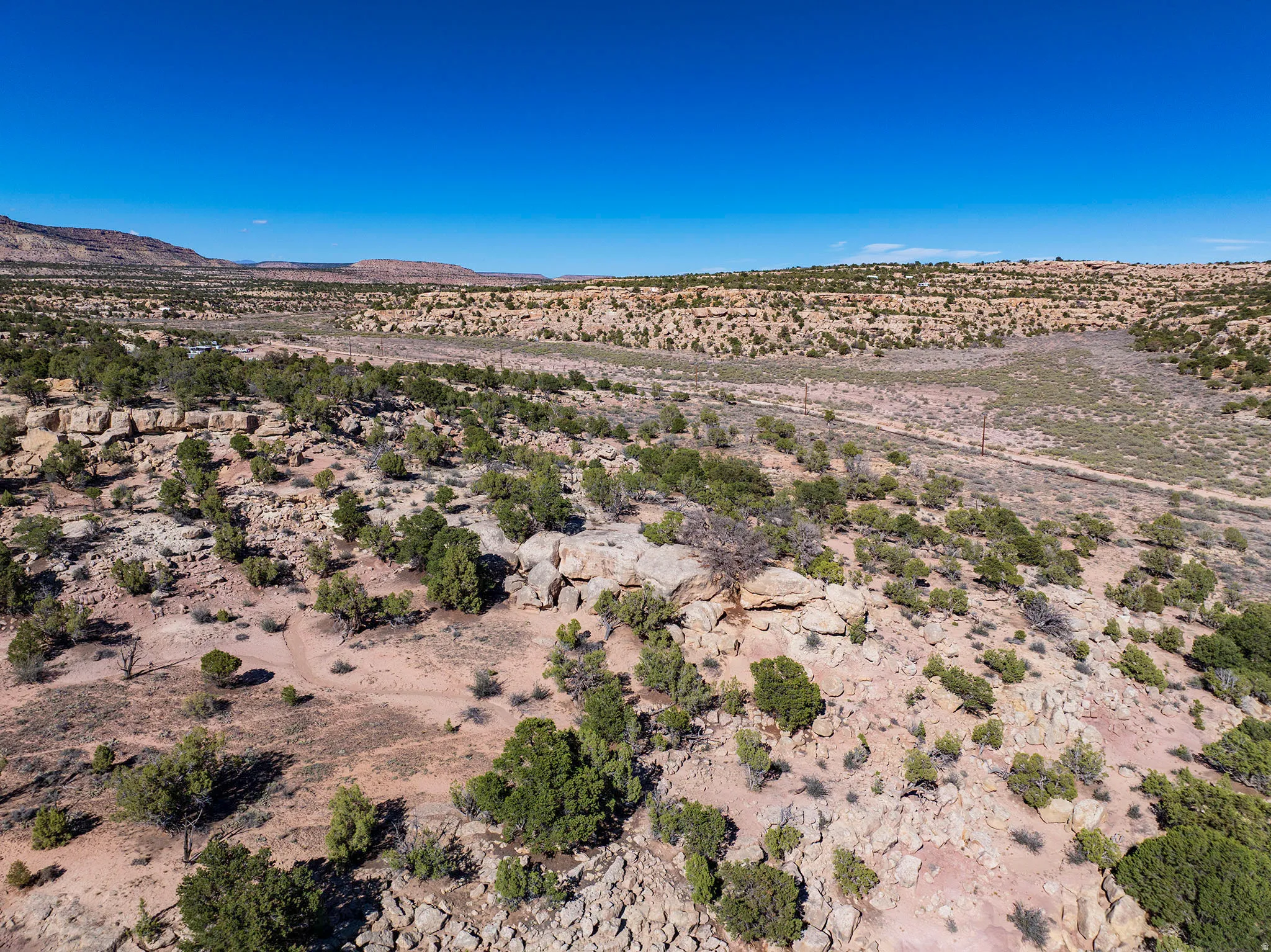 Expansive desert landscape featuring varied terrain, scattered native vegetation, and distant mountain ranges