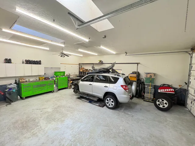 Spacious garage featuring a concrete floor, overhead fluorescent lighting, and a ceiling fan