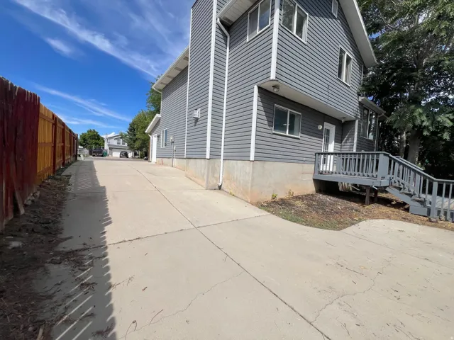 Siding exterior with multiple windows, concrete driveway, and a wood privacy fence